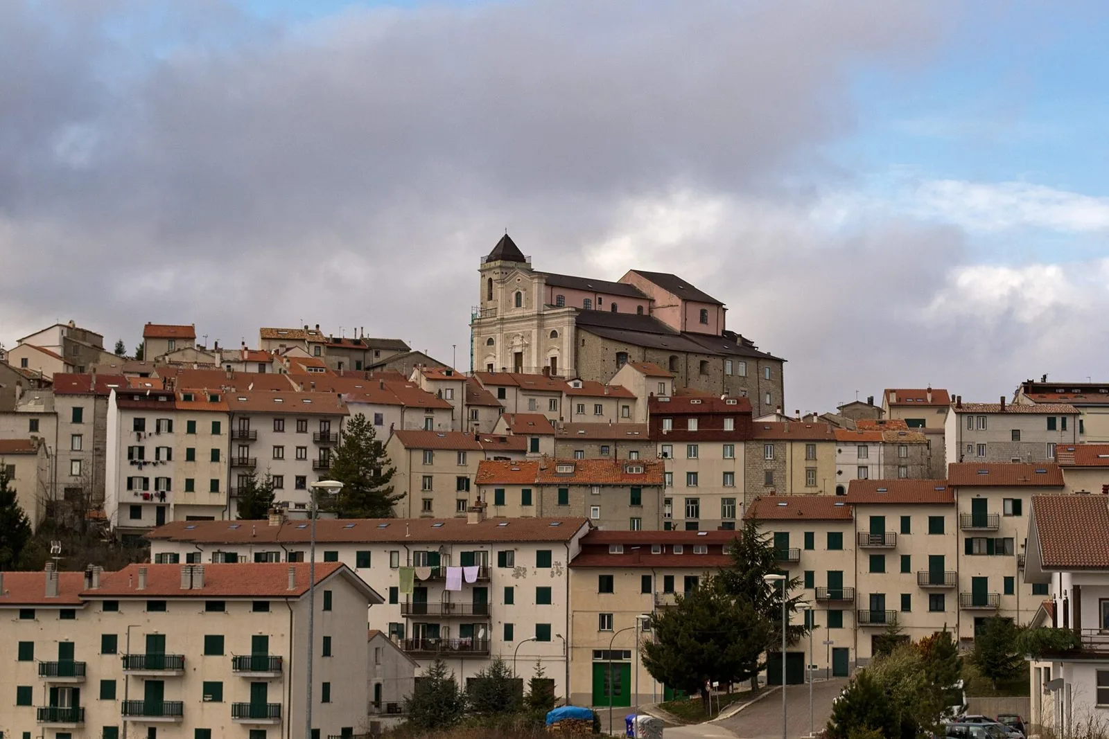 Le case di Capracotta disposte sul pendio con la chiesa madre in cima al paese sotto un cielo nuvoloso
