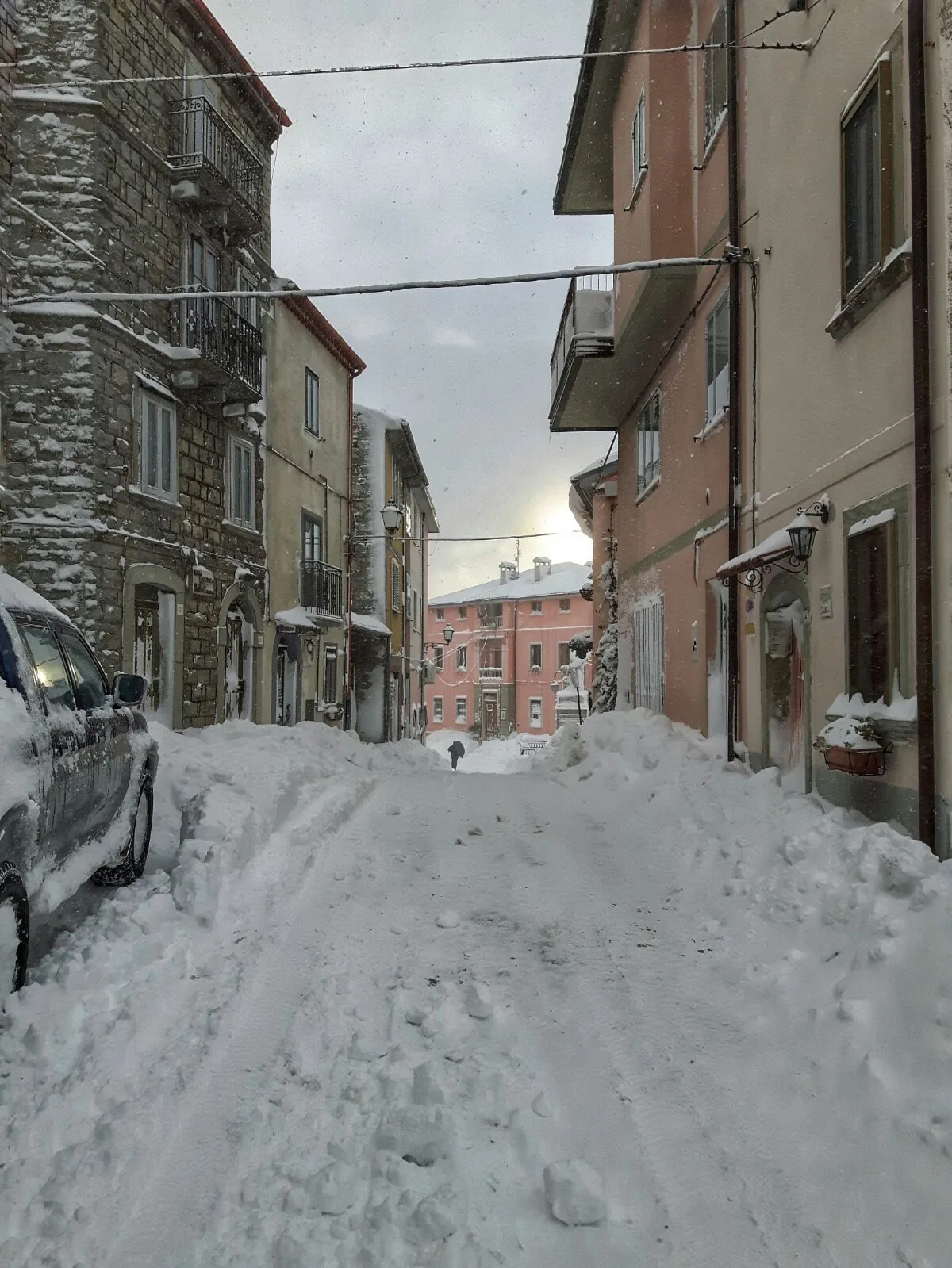 Strada di un borgo dell'Alto Molise coperta di neve fresca tra case in pietra e facciate colorate